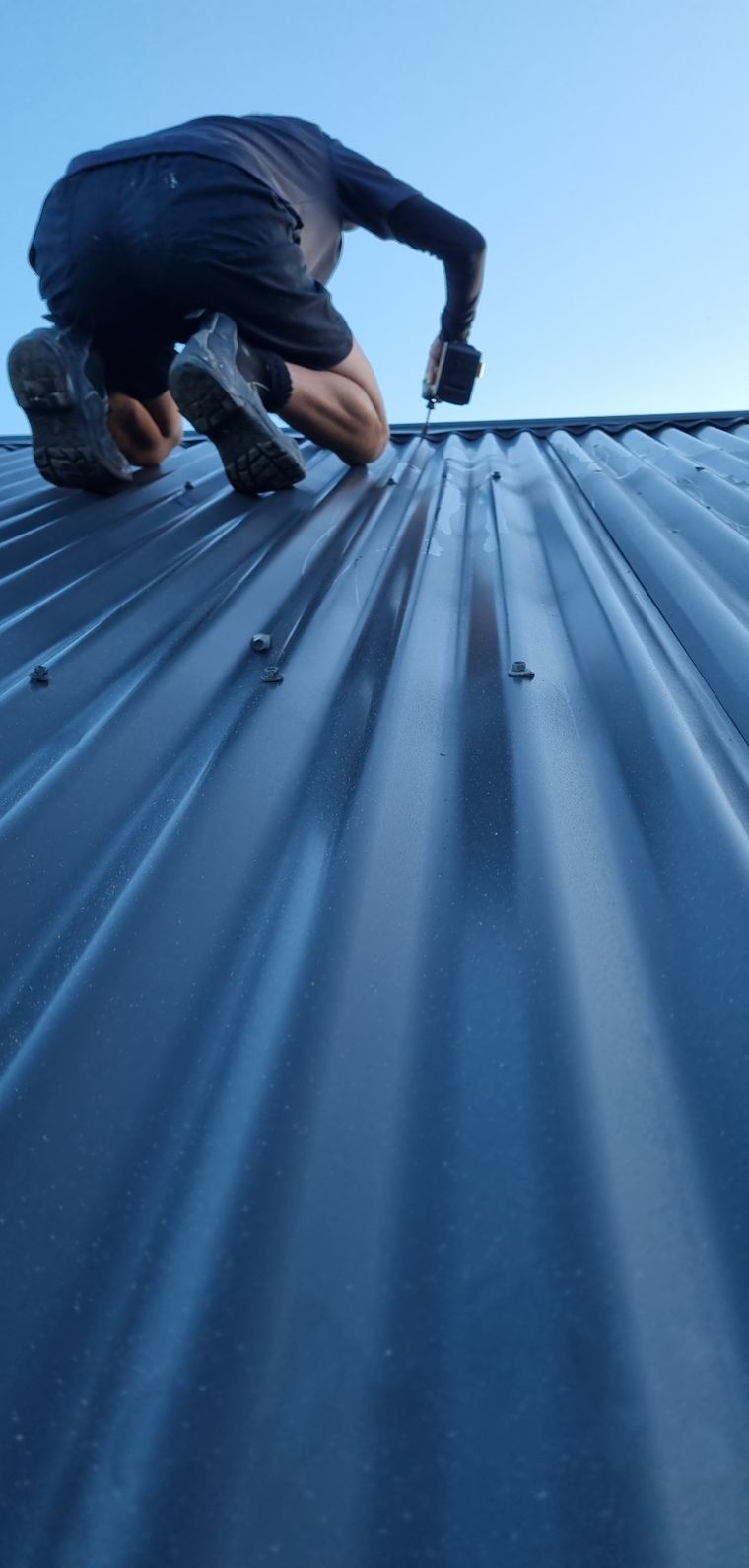 Builder installing metal roofing on home extension in Wellington