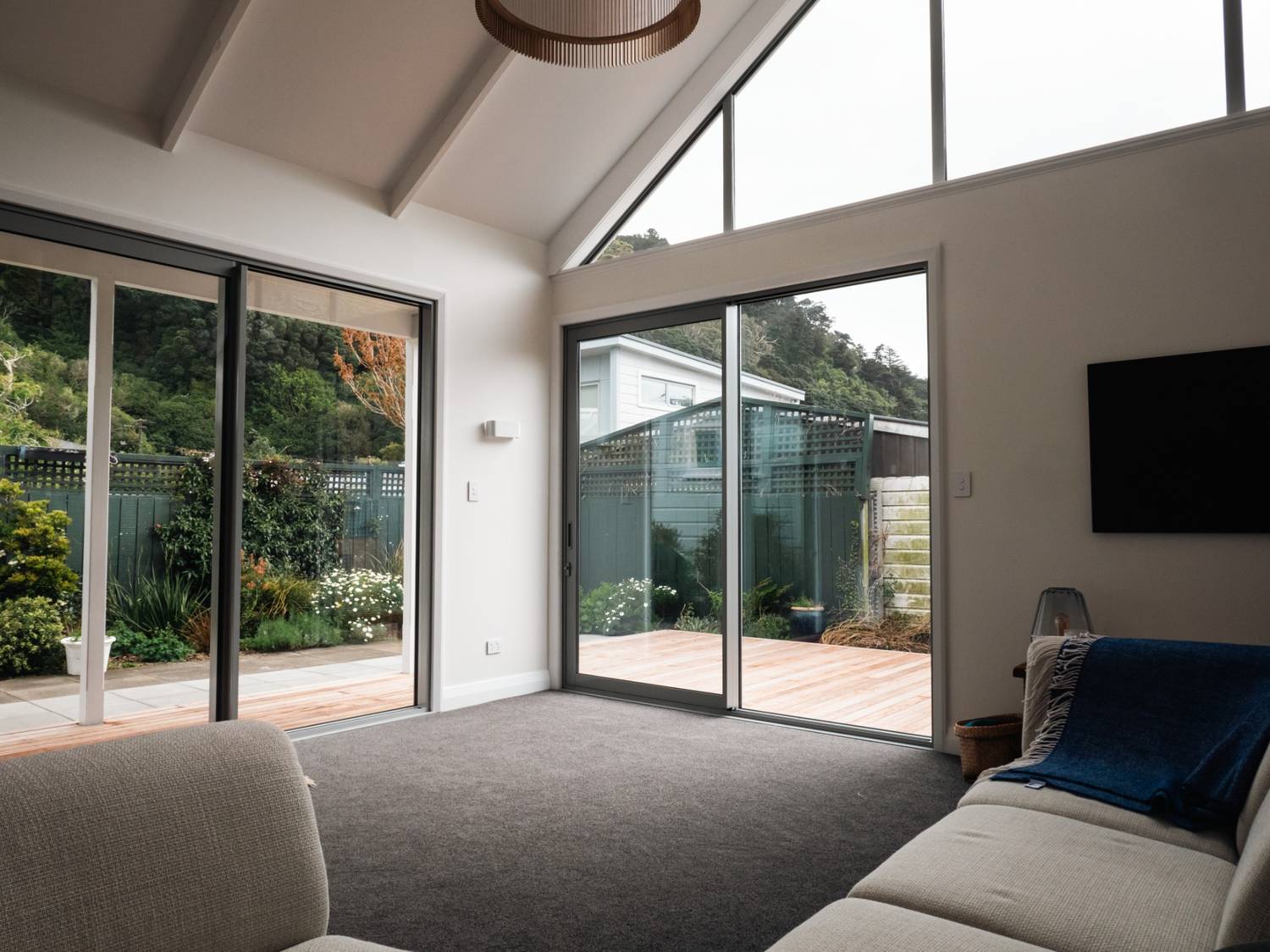 Renovated villa living room in Thorndon, Wellington by Clearcut Building Solutions, featuring large sliding doors, high ceilings, and seamless indoor-outdoor flow.