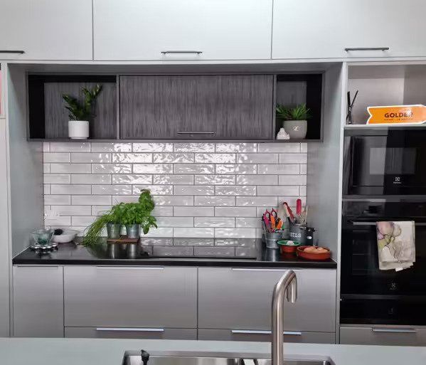 Sleek kitchen with glossy tiled splashback and modern storage from a renovation in Lower Hutt.